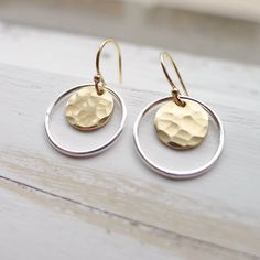 "Hammered 1/3\" gold medallions are encased by sterling silver hoops and dangle from gold filled French hook earwires. Rubber ear clutches included to avoid loss. ~ 1/2\" drop. Lightweight and easy to wear, these dainty earrings also make a great gift. They come in a cute box ready for giving. Dangle Earrings | Mixed Metal Earing | Hammered Gold Coin | Silver Circle Earing | Two Tone Jewelry | Artisan Made | Gift for Women" Hammered Metal Earrings, Modern Brass Jewelry For Anniversary, Hammered Yellow Gold Circular Earrings, Yellow Gold Circle Brass Earrings, Yellow Gold Circle Earrings In Brass, Yellow Gold Hammered Circle Earrings, Silver Round Brass Hoop Earrings, Recycled Gold Dangle Jewelry For Gifts, Recycled Gold Dangle Jewelry Gift