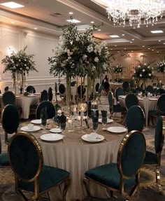 a banquet room set up with tables and chairs for formal function, including centerpieces