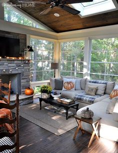 a living room filled with furniture and a fire place under a window covered in fall decorations