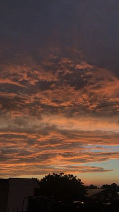 the sky is filled with colorful clouds as the sun sets in the distance behind some buildings