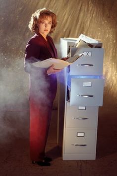 a woman standing next to a filing cabinet