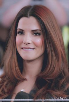 a woman with long red hair is smiling for the camera while wearing a black dress