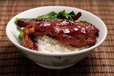 a white bowl filled with rice and meat next to broccoli on a table