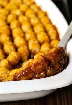 a close up of a plate of food with tater tots on it and a fork