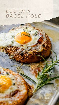 an egg in a bagel hole on a baking sheet with rosemary sprigs