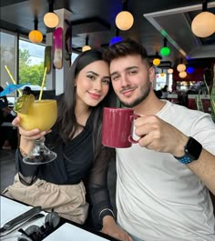 a man and woman holding drinks in their hands