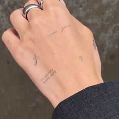 a person's hand with tattoos on it and a ring in their left hand