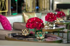 red flowers are in vases on the tables at a restaurant with gold and green chairs