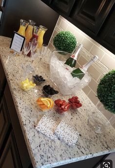 a kitchen counter topped with lots of fruit and drinks