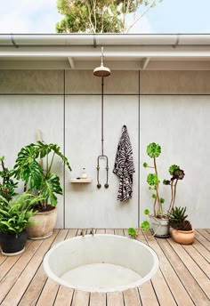 an outdoor shower is surrounded by potted plants and other greenery on the deck