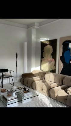 a living room filled with furniture and paintings on the wall next to a coffee table