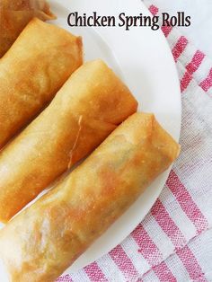 three chicken spring rolls on a plate with a red and white checkered table cloth