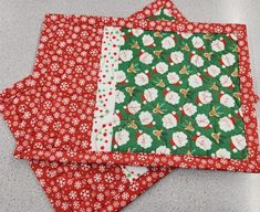 two red and green quilted placemats sitting next to each other on a table