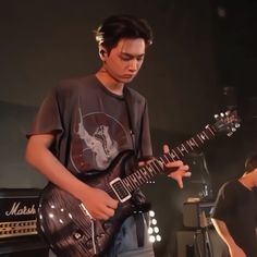 a young man playing an electric guitar on stage