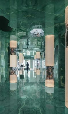 a person standing in a large room with green marble flooring and chandeliers hanging from the ceiling