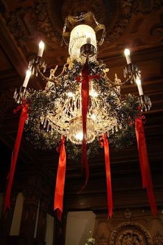 a chandelier decorated with red ribbon and lights