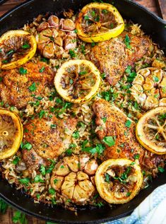 a skillet filled with chicken, rice and lemons