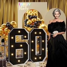 a woman standing in front of a large number 50 sign with balloons and streamers