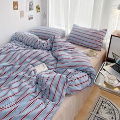 a bed covered in blue and red striped sheets with a laptop on top of it