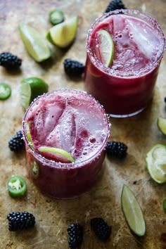 two glasses filled with blackberry margaritas and lime slices