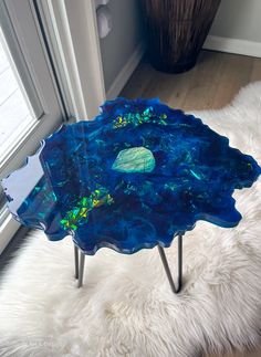 a blue glass table sitting on top of a white furnishing next to a window