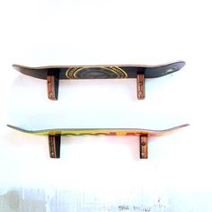 two skateboards sitting on top of each other in front of a white wall and one is upside down