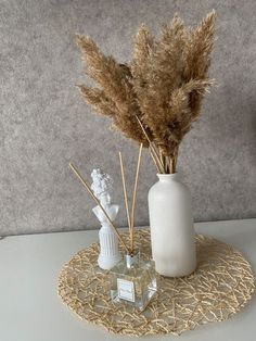 two vases with dried plants in them on a table