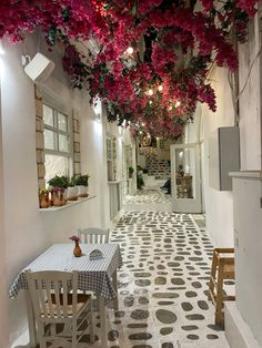 an indoor dining area with tables, chairs and flowers hanging from the ceiling above them