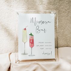 a sign that is on the side of a bed next to a glass with a drink in it