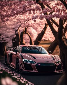 a pink car parked on the side of a road next to trees with blossoming flowers