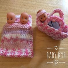 two baby dolls in a pink and white knitted bag next to a doll's purse