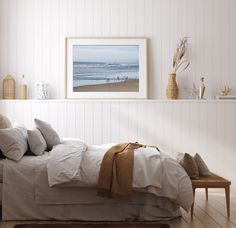 a bed with white sheets and pillows in a room next to a wall mounted art piece