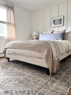 a large bed sitting on top of a wooden floor next to a window in a bedroom