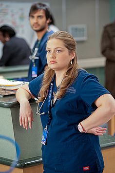 a woman in scrubs standing next to a counter with her hands on her hips