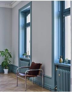 a chair sitting in front of a window next to a potted plant on top of a hard wood floor