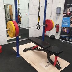 a gym with bench, barbells and weight plates