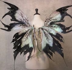 a white mannequin with black and green wings