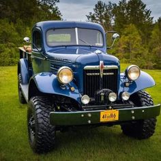 an old blue truck is parked in the grass