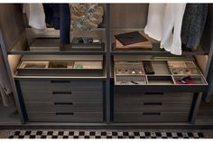 an organized closet with drawers and clothes hanging on the wall, along with checkered rugs