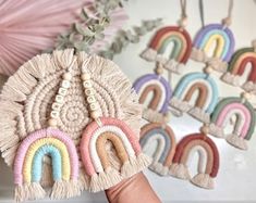 a hand holding up some tassels in front of a wall with rainbow decorations on it