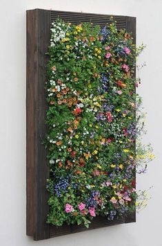 a wooden frame with flowers growing on the side of it and attached to the wall