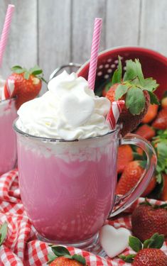 two mugs filled with whipped cream and strawberries on a checkered table cloth