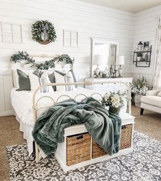 a white bed with green blankets and pillows on it in a room filled with furniture