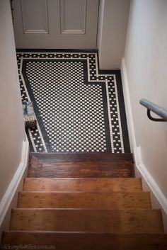 a stair case with black and white tile on the floor next to a door way