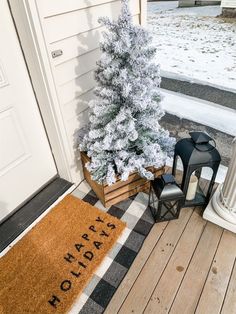 a christmas tree on the front porch next to a lantern and door mat that says happy holidays