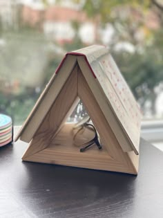 an open book sitting on top of a wooden table next to a window sill