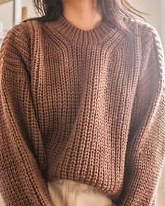 a woman wearing a brown sweater and tan pants