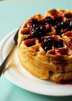 a stack of waffles sitting on top of a white plate next to a fork