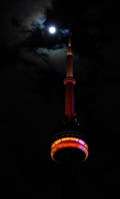 the moon is shining brightly over a tall tower