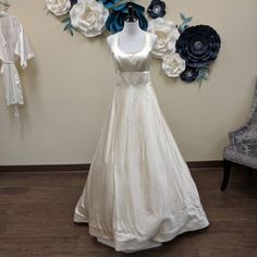 a white wedding dress on display in front of a wall with blue and white flowers